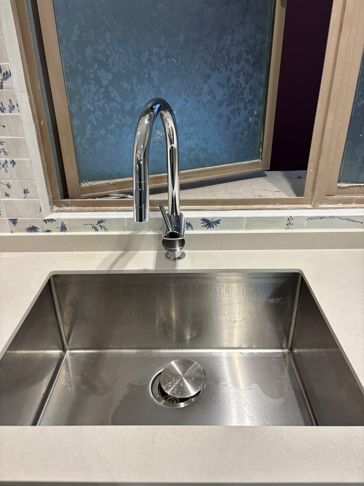 A newly installed chrome kitchen mixer over a stainless undermount sink